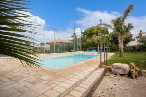 una piscina in un parco con una palma di Villa a 300 Mt. dal Mare (Magaggiari) con campo da tennis a Cinisi