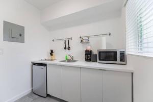 - une cuisine blanche avec évier et four micro-ondes dans l'établissement Wonderful and calm studio in Miami, à Miami