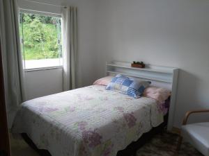 Dormitorio pequeño con cama y ventana en QUARTO CASA FREDERICO, en Domingos Martins