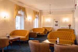 a waiting room with orange chairs and tables at Grant Arms Hotel in Grantown on Spey