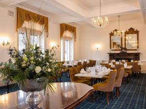 ein Restaurant mit Tischen, Stühlen und einem Spiegel in der Unterkunft Grant Arms Hotel in Grantown on Spey