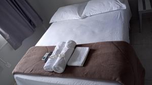 a bed with two towels and a book on it at Hotel Rota 282 in São Miguel dʼOeste