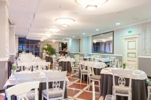 una sala da pranzo con tavoli e sedie bianchi di Europe Hotel a Minsk