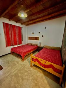 two beds in a room with red sheets at Rochabus in Ica