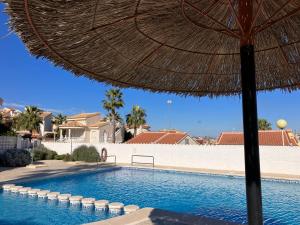 een zwembad met een parasol naast een resort bij Villa South in Ciudad Quesada