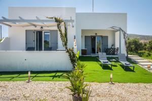 a white house with a yard with green grass at Milos Swell Suites II in Pollonia