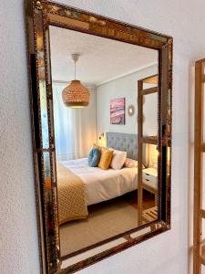 uno specchio che riflette un letto in una camera da letto. di Villa Yoli, céntrico con plaza de garaje ad Avilés