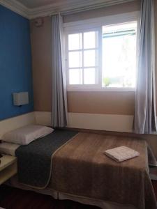 Schlafzimmer mit einem großen Bett und einem Fenster in der Unterkunft Hotel Bonnel Eirelli - Tropical in Cachoeira do Sul