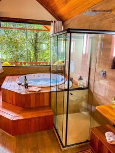uma banheira de hidromassagem num quarto com um recinto de vidro em Chalés Princesa Isabel em Petrópolis