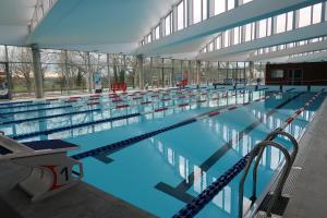 a large swimming pool with blue water in a building at Le Sophora in Chéu