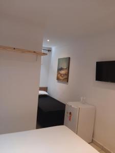 a room with a bed and a small refrigerator at Pippo Suites Guarujá in Guarujá