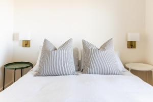 1 cama blanca con 2 almohadas y 2 mesas en Blanche de l'Ouest - Îles de la Madeleine, en Havre-Aubert
