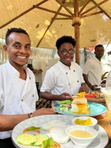 two men in a kitchen with a plate of food at Kahawa house in Zanzibar City