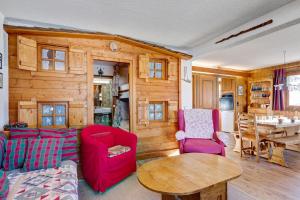 ein Wohnzimmer mit roten Stühlen und einer Holzwand in der Unterkunft Charming flat with garden nearby the slopes - Welkeys in Megève
