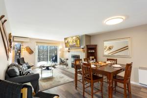 a dining room and living room with a table and chairs at Tremblant Rocher Soleil Ski In Ski Out 2 Bedroom in Mont-Tremblant