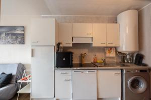 a kitchen with white cabinets and a washer and dryer at Nart & Niar in Annemasse