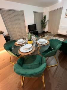 ein Wohnzimmer mit einem Glastisch und grünen Stühlen in der Unterkunft Dartford Lux Stay one bedroom apartment in Dartford