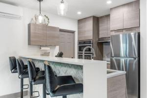 cocina con barra con sillas y nevera en Lauderdale Modern 1 Bedroom 1 Bathroom with Private Backyard, en Fort Lauderdale