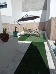 a patio with a table and an umbrella at *APPARTEMENT NEUF AVEC TERRASSE À LA MARSA*** in La Marsa