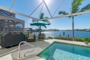 a swimming pool with a television and an umbrella at Southern Exposure I Waterfront 5 Bed House I Wide Water Views of Landmark Bay in Marco Island