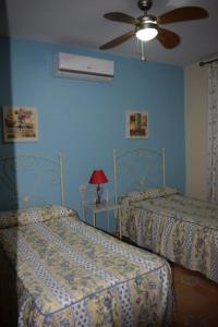 two beds in a bedroom with blue walls and a fan at El Manantial in Jerez de los Caballeros