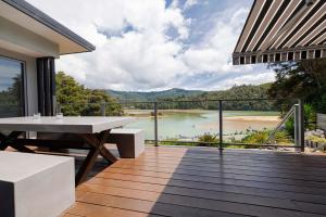 a balcony with a table and a view of a river at Luxury in Kaiteriteri in Kaiteriteri
