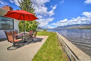 Waterfront Osoyoos Lake Cottage with Beach and Patio! في Oroville: طاولة وكراسي مع مظلة بجانب الماء