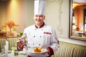 
a man in a chef's outfit holding a plate of food at Europe Hotel in Minsk

