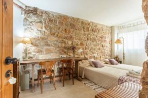 a bedroom with two beds and a table in front of a stone wall at Mas Coquells, preciosa masia en plena natura in Vilanant