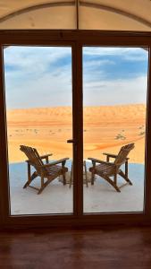 een raam met uitzicht op een tafel en stoelen bij alsaif camp in Badīyah