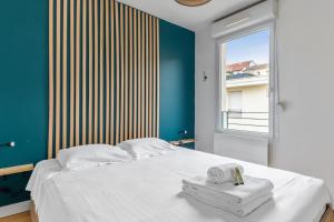 1 dormitorio con 1 cama con toallas y ventana en City house with garden near Part-Dieu in Lyon - Welkeys, en Lyon