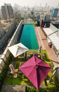 a pool with umbrellas and chairs next to a building at Mercure Bangkok Siam in Bangkok