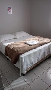 a bed with a brown blanket on top of it at Hotel Rota 282 in São Miguel dʼOeste +6 photos