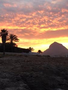 un coucher de soleil avec des palmiers et une montagne en arrière-plan dans l'établissement Casita Pepe, à Jávea