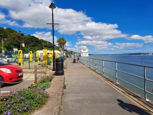 un trottoir à côté d'une masse d'eau avec un phare dans l'établissement SeaView Apartment Suite, à Cobh