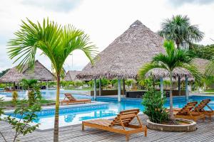 a resort swimming pool with chairs and palm trees at Irapay Amazon Lodge - Asociado Casa Andina in Padre Cocha
