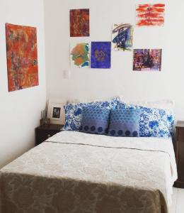 a bedroom with a bed with blue pillows and paintings on the wall at Rooftop Paradise Central Location, Scenic Views in Mexico City