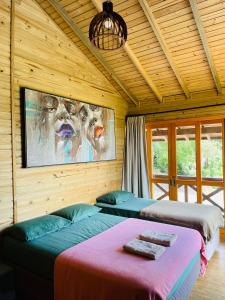 two beds in a room with a painting on the wall at Morada Guarda Explorer 01 in Guarda do Embaú