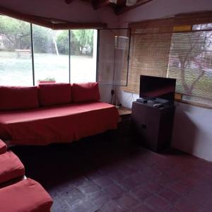 sala de estar con sofá rojo y TV en cabañas fátima en Villa Las Rosas