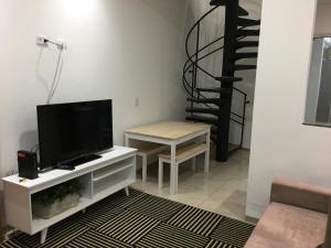 a living room with a flat screen tv and a table at Loft próximo a UFMS in Campo Grande
