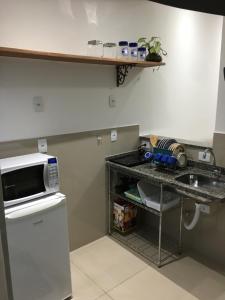 a kitchen with a sink and a counter with a microwave at Loft próximo a UFMS in Campo Grande