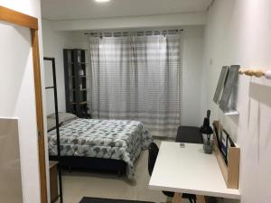 1 dormitorio con cama, mesa y ventana en Loft próximo a UFMS, en Campo Grande