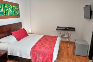 a bedroom with a bed with a red pillow and a chair at Hotel Volare in Armenia