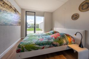 a bedroom with a bed with a colorful comforter and a window at Ostreahof Gezin & Familie vakantiehuis aan strand en jachthaven in Kamperland