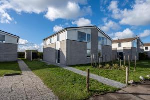 a brick house with glass windows on a lawn at Ostreahof Gezin & Familie vakantiehuis aan strand en jachthaven in Kamperland