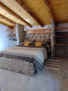 Cama en habitación con pared de piedra en Cabaña Los Abedules en Villa Pehuenia
