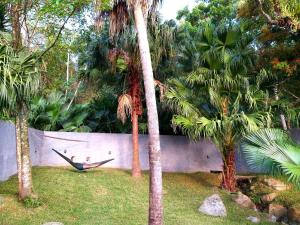 a man laying in a hammock between two palm trees at Morada Guarda Explorer 01 in Guarda do Embaú