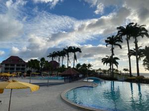 uma piscina num resort com palmeiras e o oceano em Pierre et Vacances Vue Mer em Sainte-Luce