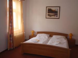 a bedroom with a bed with white sheets and a window at Penzion Haus Regrus in Jáchymov