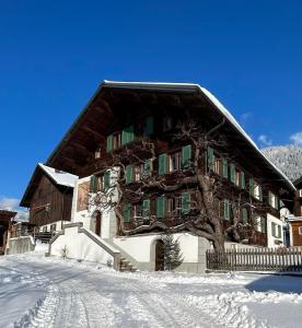 um grande edifício com uma árvore na neve em Haus Mangard em Sankt Gallenkirch